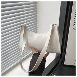 Close-up of creamy patent leather baguette bag with natural shadow lighting and metal buckle