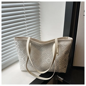 Close-up of cream tote bag featuring intricate geometric jacquard pattern and leather straps