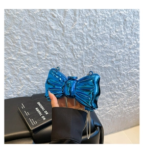 Macro view of metallic blue bow clutch bag featuring a unique pleated textured finish