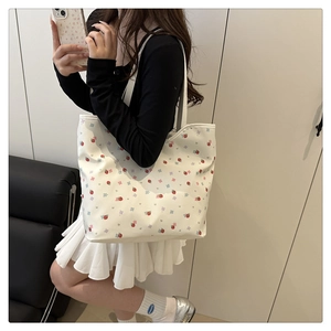 Close-up detail of white canvas tote bag with vibrant red strawberry and floral patterns