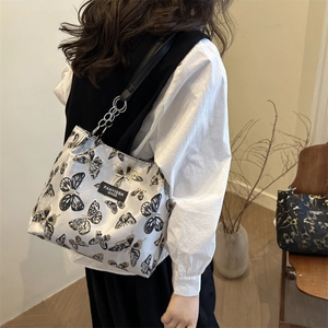 Sac à épaule argenté chic à motif papillon avec bandoulière chaîne porté par mannequin