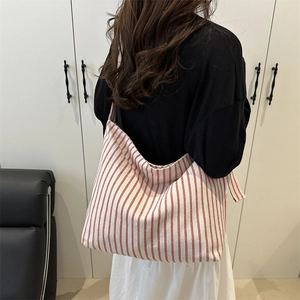 Red and beige striped canvas tote bag with large capacity shown on model back shoulder