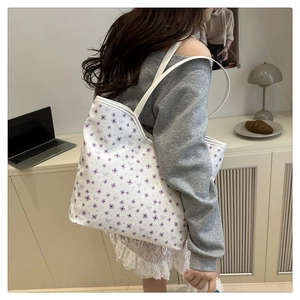 Side view of white shoulder tote bag with purple floral pattern and bow details