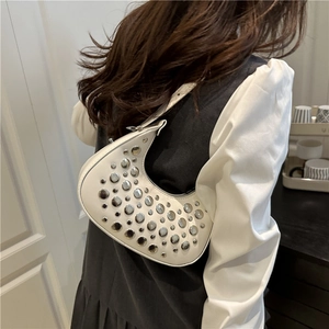 White crescent half-moon shoulder bag with silver rivet studs on a female model