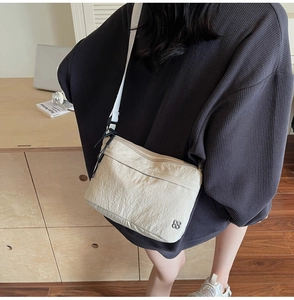 Detail of beige wrinkled nylon crossbody bag with wide strap and floral metal logo