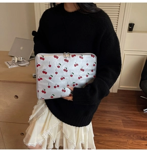 Silver leather laptop sleeve with red cherry print and dual metal zippers shown in hand