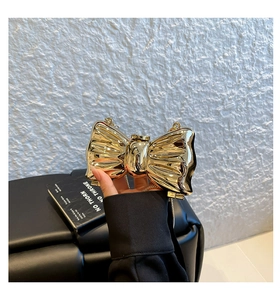 Detailed close-up of a golden butterfly-shaped metallic clutch with mirror finish and chain