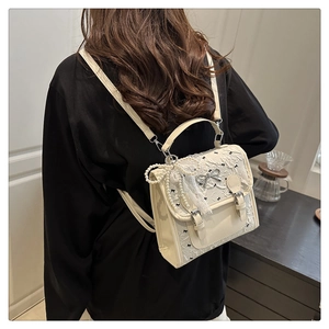 Detail of a cream lace backpack featuring pearl chains and mini black bow decorations