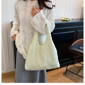 Détail d'un sac cabas en tissu vert clair avec de délicats motifs brodés de fleurs