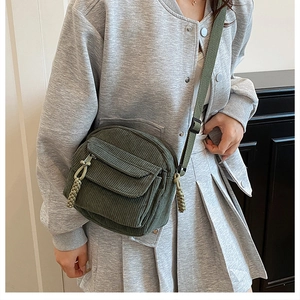 Detail of dark green corduroy crossbody bag texture and adjustable woven strap
