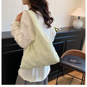 Détail de la broderie florale vintage sur un sac fourre-tout en toile beige à bandoulière