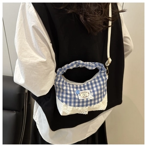 Detail of blue gingham bucket bag with lace trim and adjustable white shoulder strap