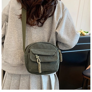 Detail view of dark green corduroy crossbody bag with zipper pocket and knotted puller