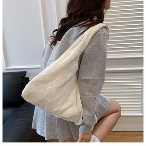Détail de broderie florale blanche sur un sac fourre-tout en mousseline respirante