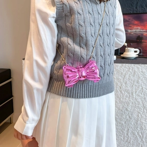 Pink butterfly bow crossbody bag with gold chain strap shown on model in stylish outfit