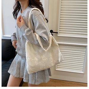 Détail d'un sac cabas blanc orné de broderies florales délicates sur le tissu