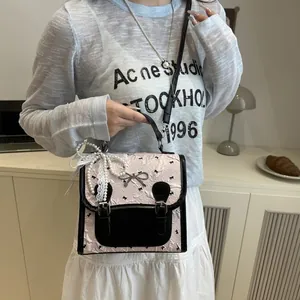 Pink preppy square bag with black bow print, pleated texture, and elegant pearl charm