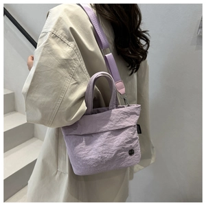 Lavender bucket bag with pleated texture shown as a stylish crossbody on a model
