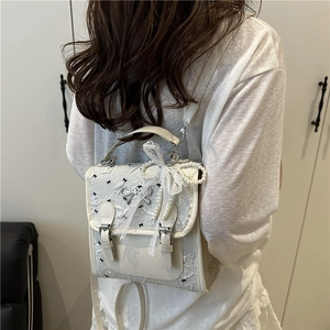White lace backpack with black bow prints, pearl chain, and silver bow hardware