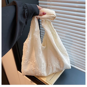 Détails de broderie florale sur un sac cabas en mousseline crème avec lumière naturelle