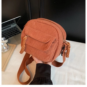 Close-up of vintage corduroy texture on orange crossbody bag with woven zipper detail