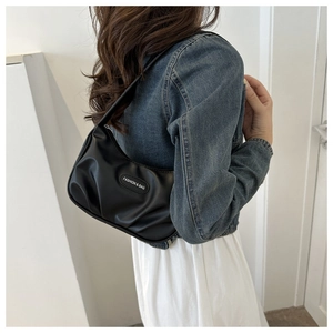 Close-up of black ruched crescent underarm bag with fashion label and zipper detail