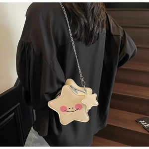 Detail of star-shaped cream crossbody bag with smiling face and silver chain strap