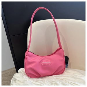 Detail of pink pleated handbag showing fashion text plaque and smooth leather texture