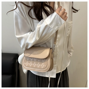 Détail du motif en cuir matelassé et du logo en métal sur le sac bandoulière beige