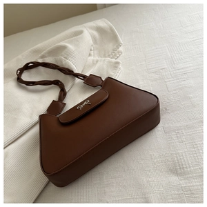 Détail du sac en similicuir marron avec bandoulière tressée et nœud argenté