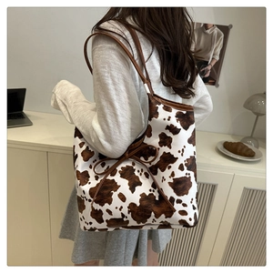 Detail of a cow print tote bag with brown straps and stylish side bow decoration