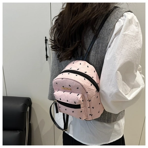 Detail of pink mini backpack with black bow patterns and wrinkled texture metal plaque