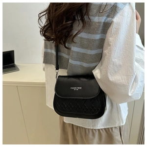 Détail du sac bandoulière noir avec coutures en losanges et lettrage argenté chic