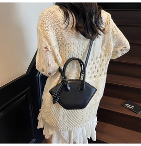 Secchiello trapezoidale nero minimalista con nodo decorativo indossato da una modella