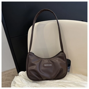 Detail of dark brown crescent bag with pleated faux leather and metallic fashion patch