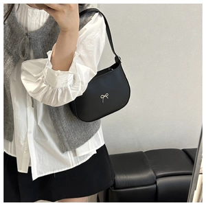 Close-up of black matte leather half-moon shoulder bag with small silver bow detail