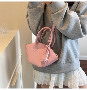 Borsa a secchiello geometrica rosa con manici ad anello e dettaglio nodo indossata