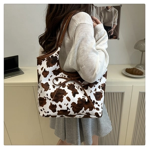 Detail of cow print tote bag with brown leather bows and stylish shoulder strap design