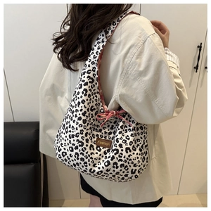 Leopard print tote bag with red-white bow detail and brown leather fashion label closeup