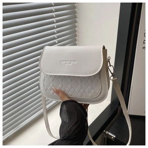 Détail du sac besace en similicuir blanc crème avec texture matelassée et boucles