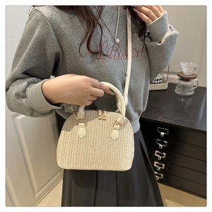 Detalle de bolsa de paja en forma de concha con cremalleras dobles y asas de PU