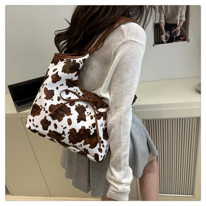 Detail of a large capacity cow print shoulder bag with brown trim and delicate bow knot