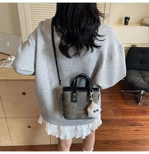 Detail of grey mini tote with black strap and cute plush charm in cozy interior