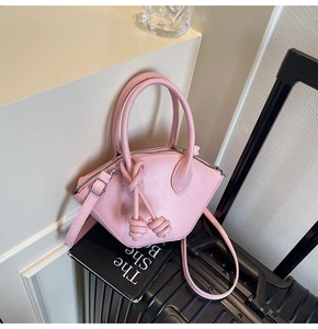 Dettaglio della borsa a secchiello geometrica rosa chiaro con zip argento e nodi