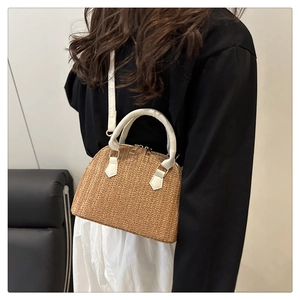 Bolso de paja con asa de cuero blanco y cremallera dorada mostrado en modelo