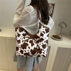 Minimalist cow print tote bag with brown bow detail in an aesthetic indoor lifestyle setting
