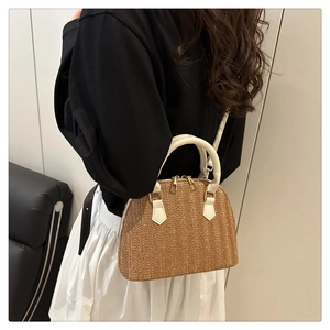 Detalle de bolso de paja trenzada con asas de cuero blanco llevado por una modelo