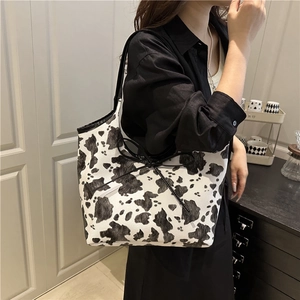 Fashionable cow print underarm bag for women with black bow detail and shoulder strap