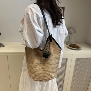 Handwoven straw tote bag with black trim and long shoulder straps for summer fashion