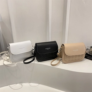 Trois sacs à bandoulière carrés minimalistes en blanc, noir et beige sur escalier